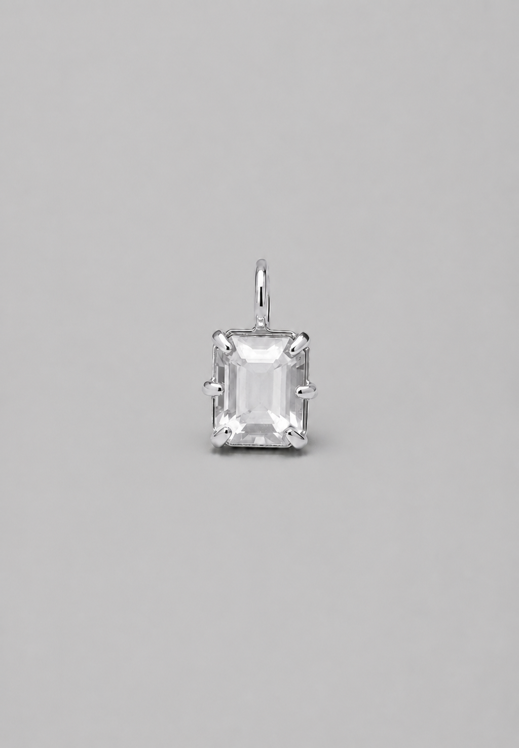 3D render of emerald-cut milky white sapphire pendant in a silver in a multi claw setting on a solid grey background.
