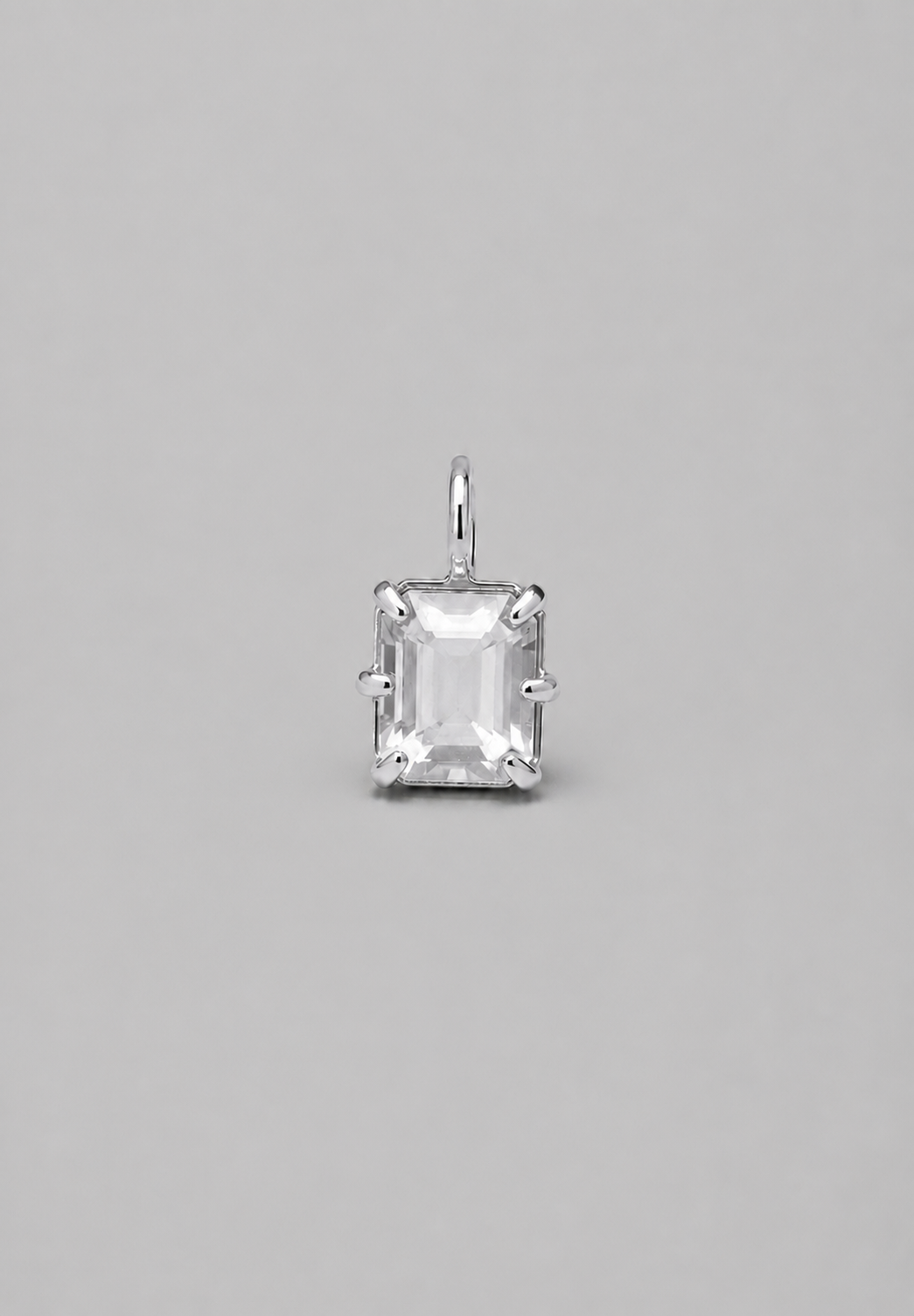 3D render of emerald-cut milky white sapphire pendant in a silver in a multi claw setting on a solid grey background.