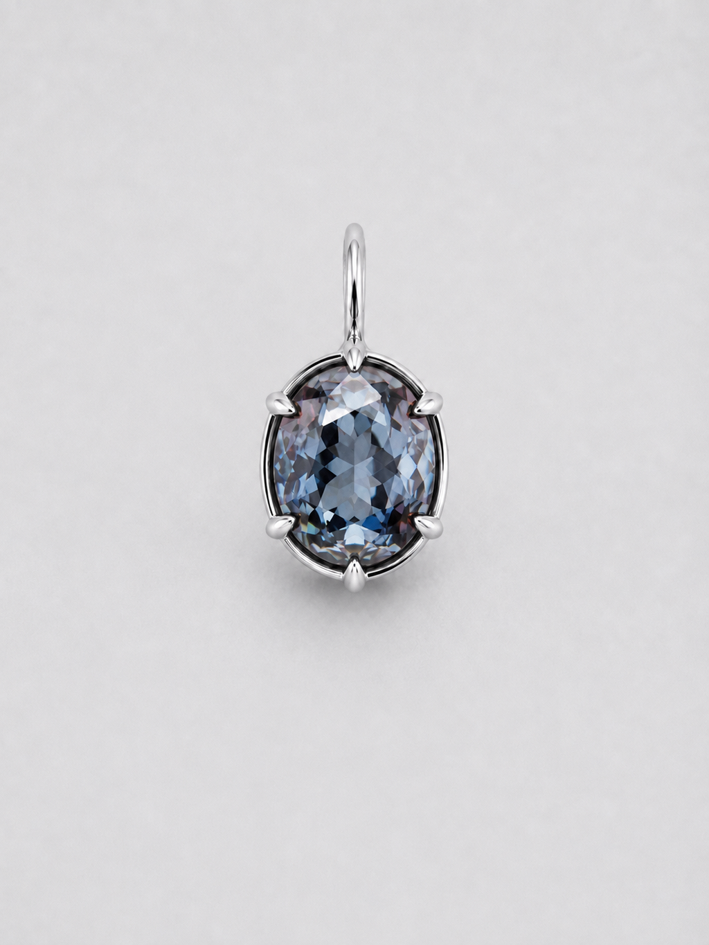 A 3D render of an oval-cut colour change sapphire pendant in a gold multi claw setting with a matching gold bail, shown on a neutral light grey background.