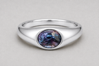 A 3D render of an oval-cut colour change sapphire flush set signet ring in a silver, shown on a neutral light grey background.