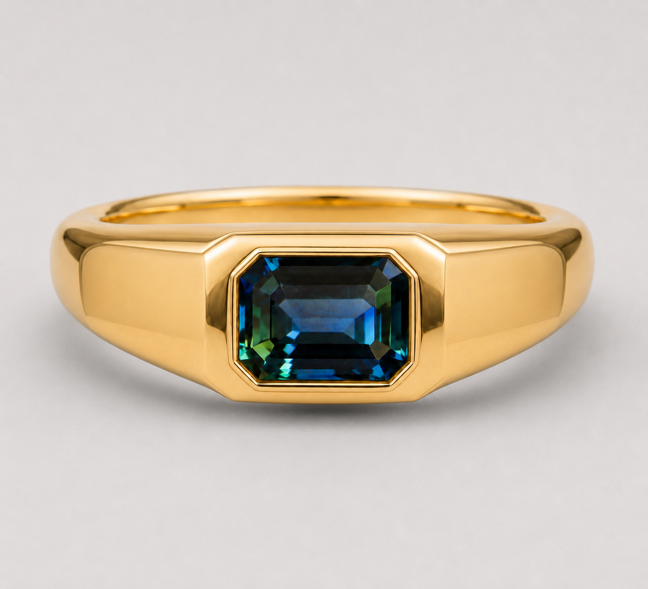 3D render of an emerald cut blue/green parti sapphire flush set in a signet style gold ring