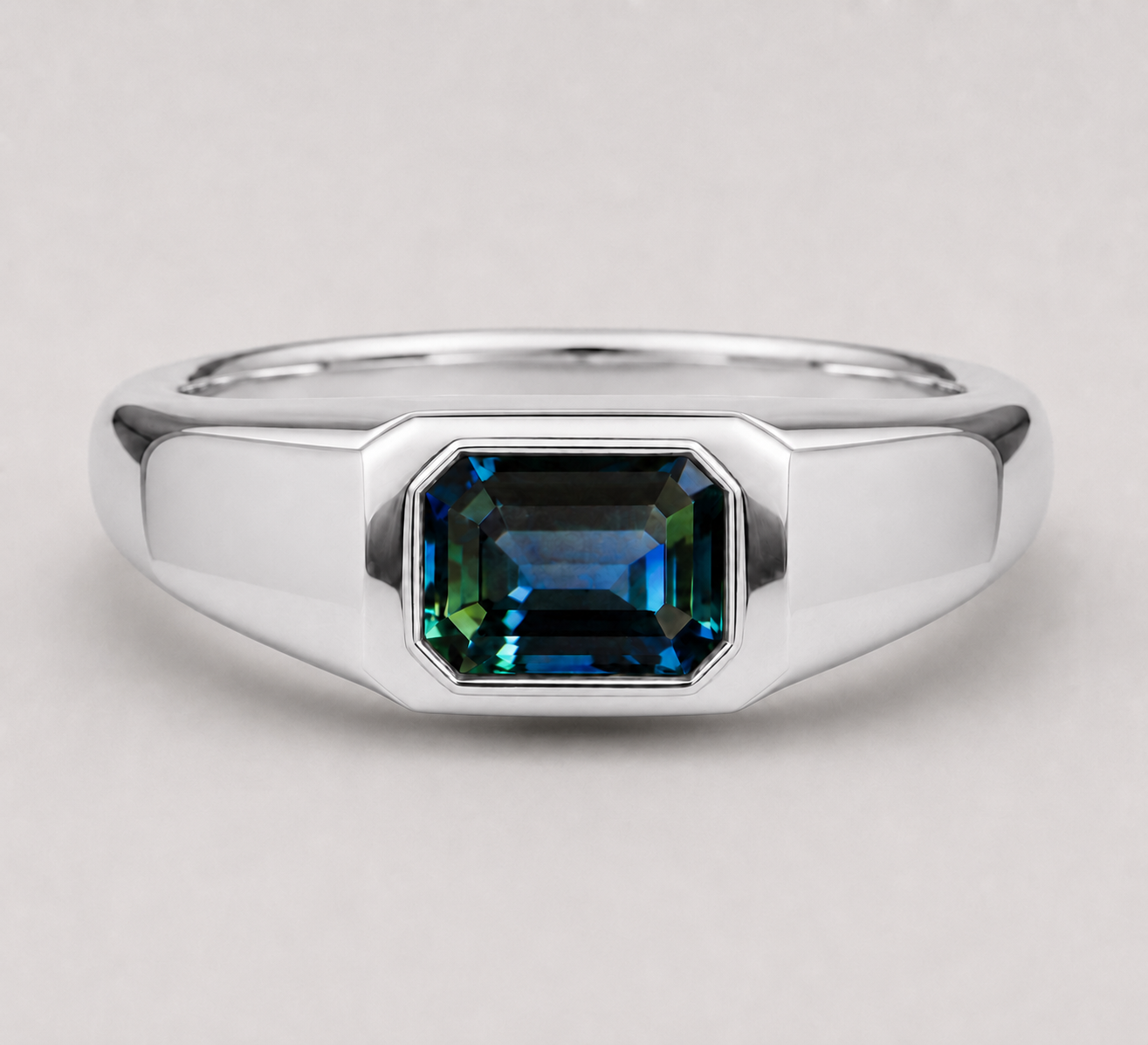 3D render of an emerald cut blue/green parti sapphire flush set in a signet style silver ring