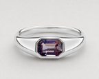 A yellow silver signet ring featuring a bezel-set emerald-cut purple spinel, shown on a neutral light grey background.