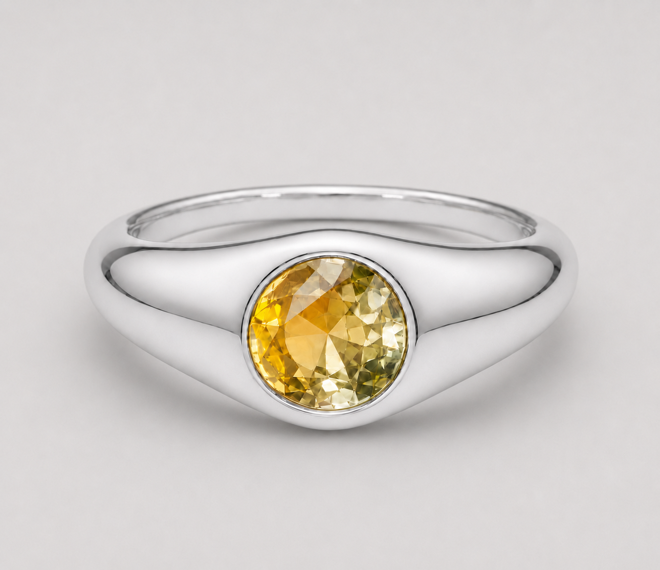 3D render of a signet style bezel set ring with a round bi-coloured yellow sapphire in sterling silver