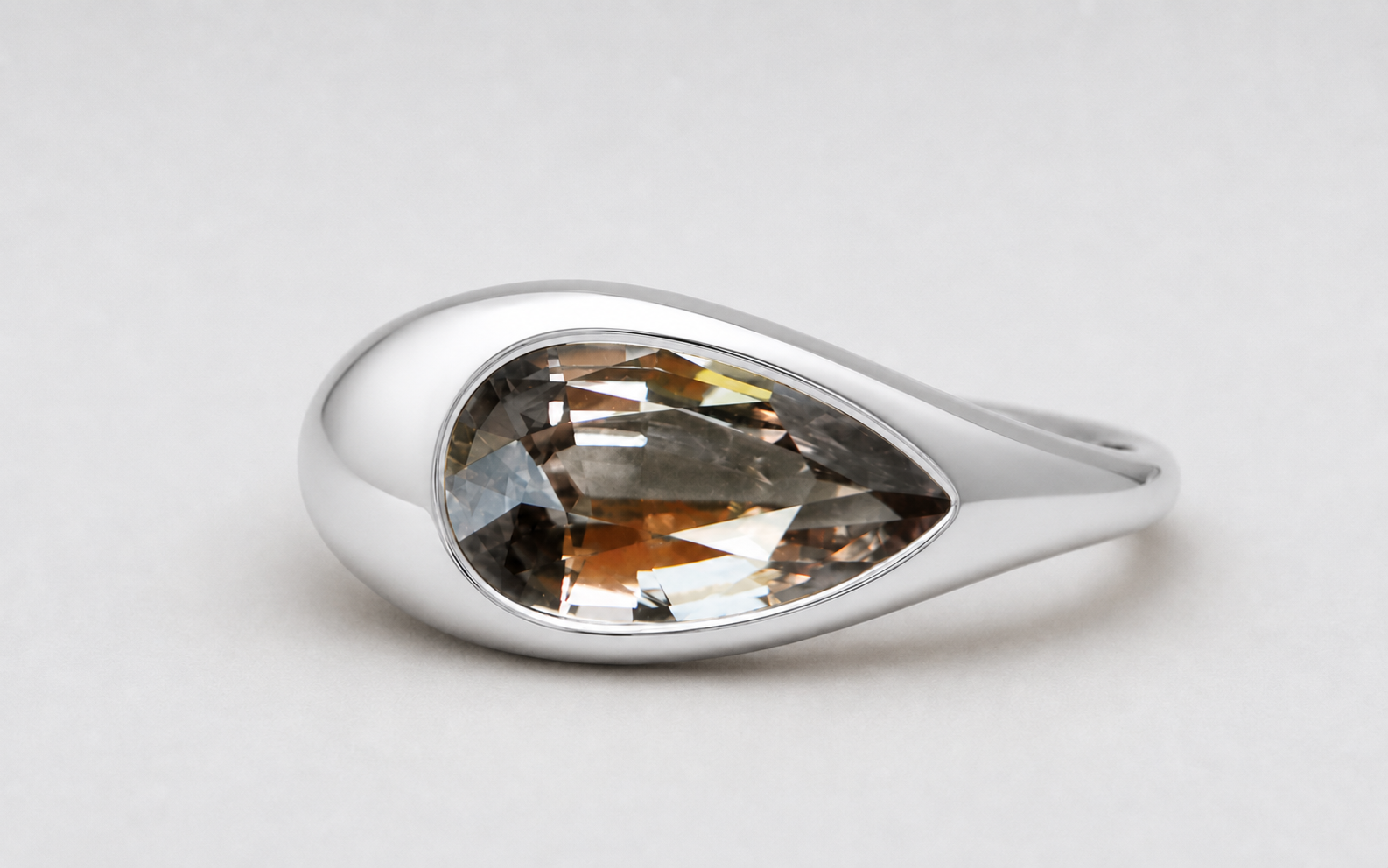 3D render of a pear shaped champagne coloured natural zircon in a sterling silver ornamental ring
