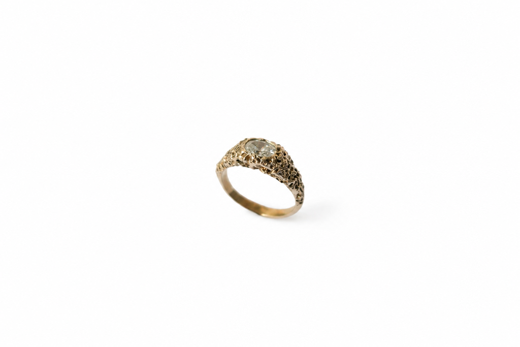 Textured gold band with a white diamond on a white background