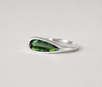 3d render of an elongated pear shape dark green tourmaline set in a sterling silver bezel set ring