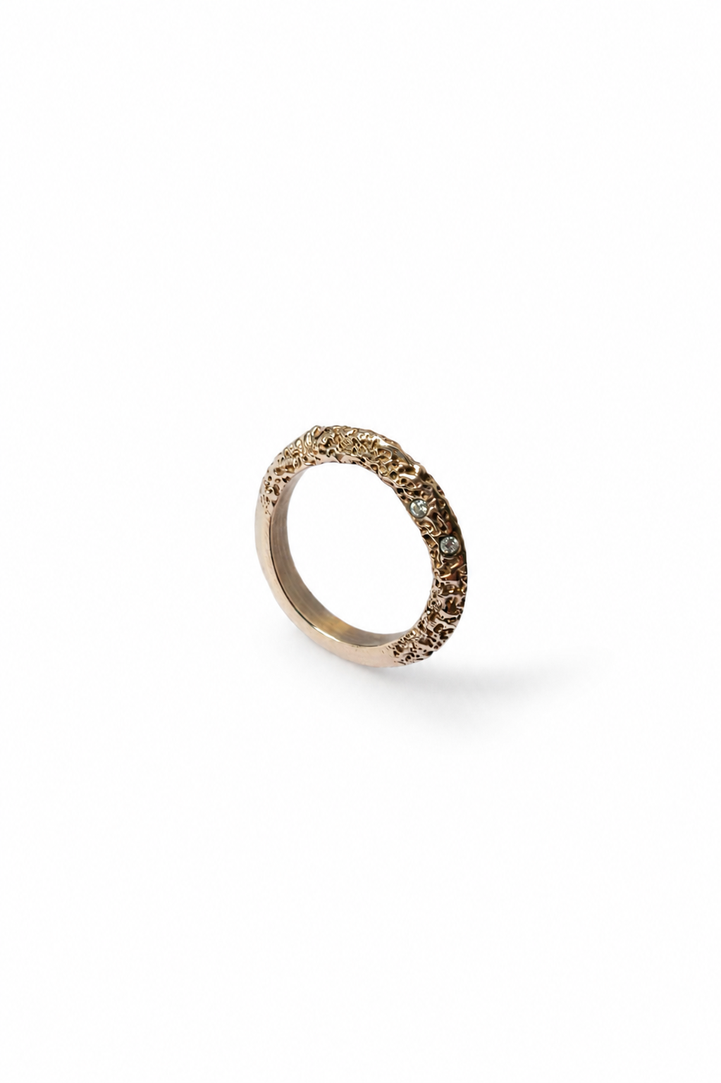 A single textured knife edge ring in a warm gold metal, photographed on a clean white background with a soft shadow.