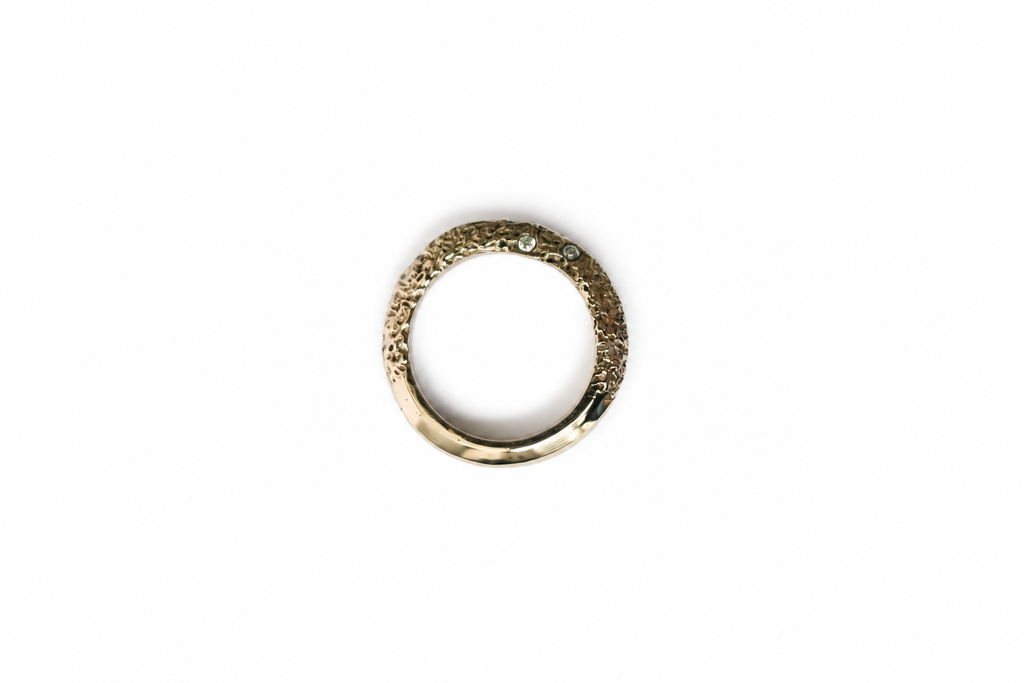 A textured gold ring with a small diamonds set in the centre, shown against a plain white background.