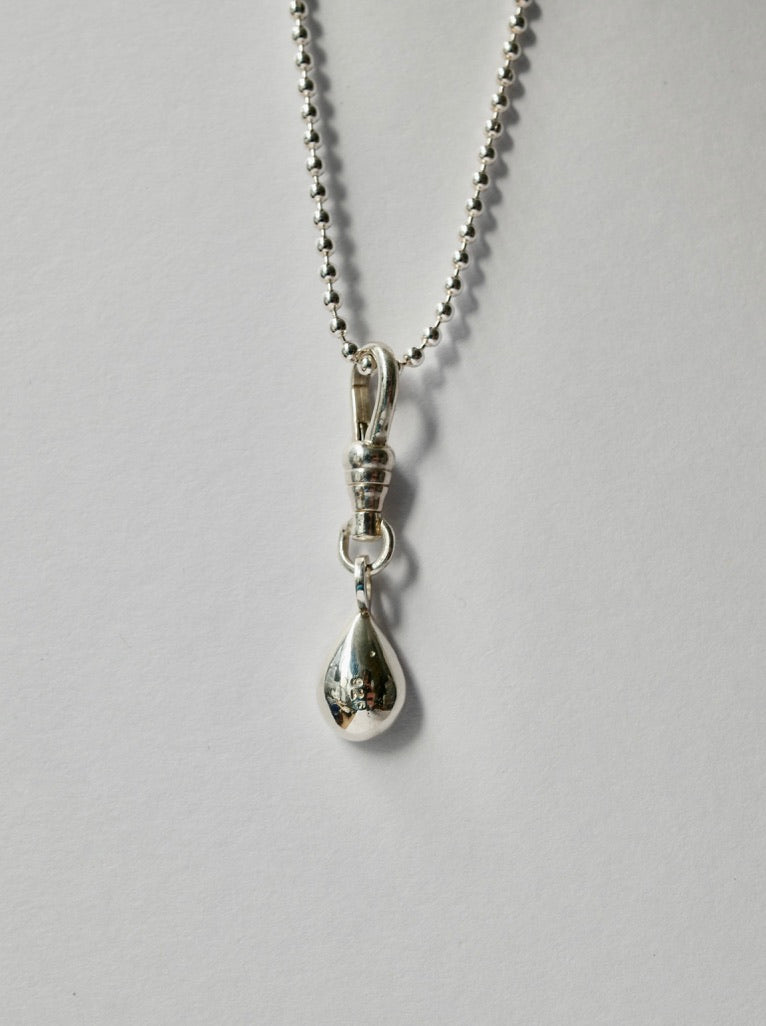 A silver teardrop pendant necklace on a silver ball chain, photographed against a plain light grey background.