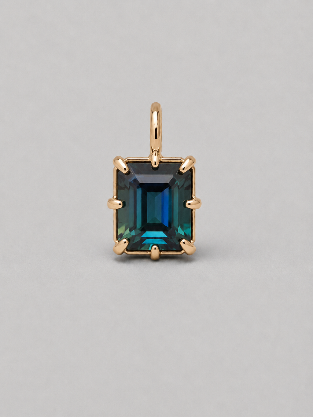 3D render of an emerald cut blue/green parti sapphire on a gold multi claw setting