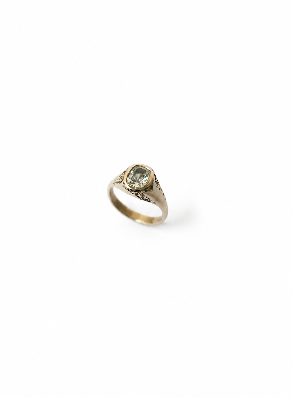 A gold signet ring with a central silver diamond, photographed on a clean white background.