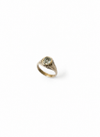 A gold signet ring with a central silver diamond, photographed on a clean white background.