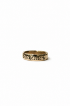 A gold band ring engraved with the gothic text 'Finche Morte' on a plain white background.