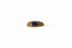 A gold ring with a textured band and a central oval blue sapphire, shown on a plain white background.