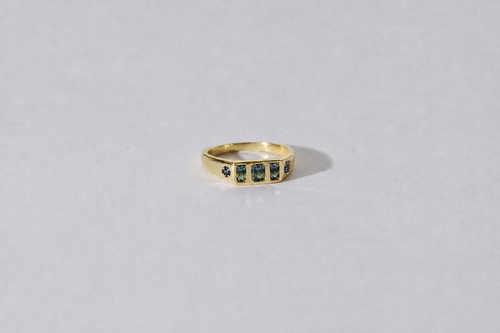 Gold ring with parti sapphires on a light grey background