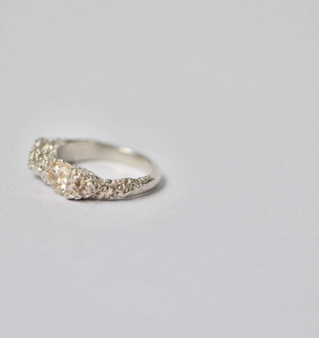 Silver ring with champagne zircon on a light grey background