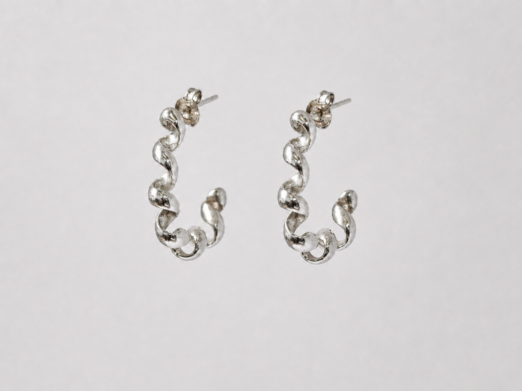 Pair of silver squiggle earrings on a light grey background