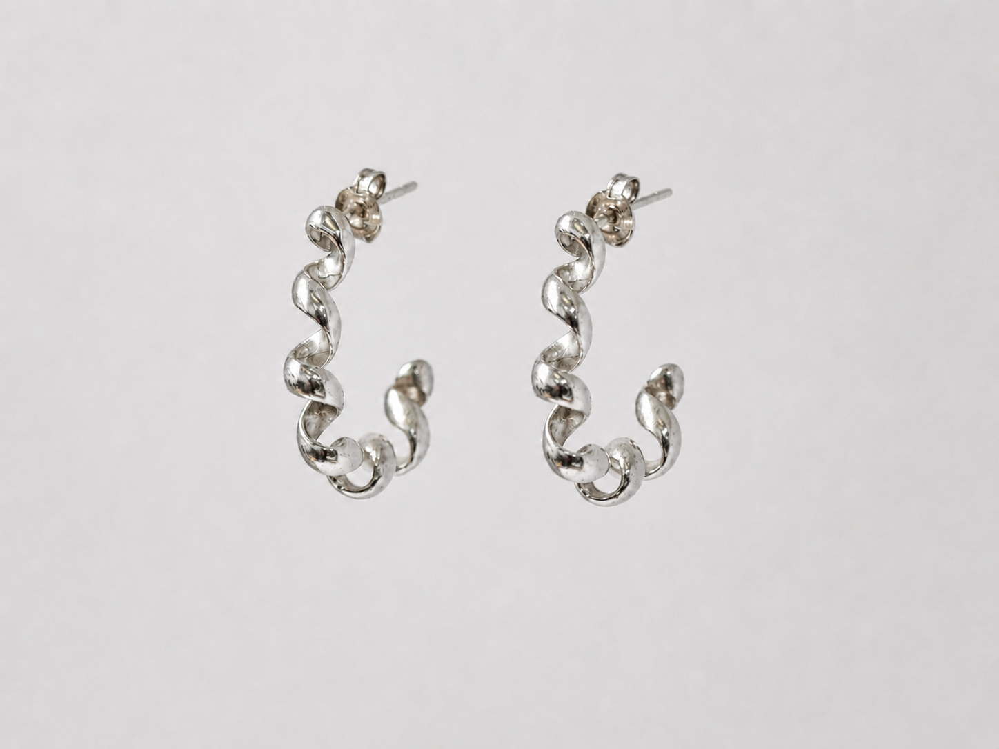 Pair of silver squiggle earrings on a light grey background