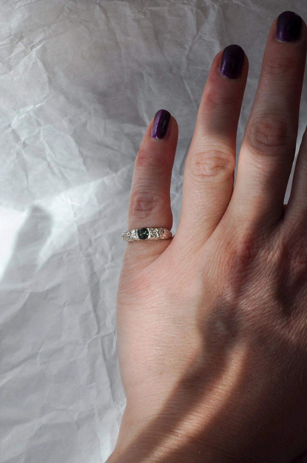 Hand with a ring on a textured white background