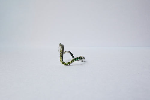 A silver wavy pavé  ring with green gemstone accents, photographed on a plain light gray background.