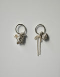 A pair of silver-toned dangle earrings on a light gray background. Each earring features a circular ring, a textured silver charm, a small white pearl, and a long twisted silver rope detail.