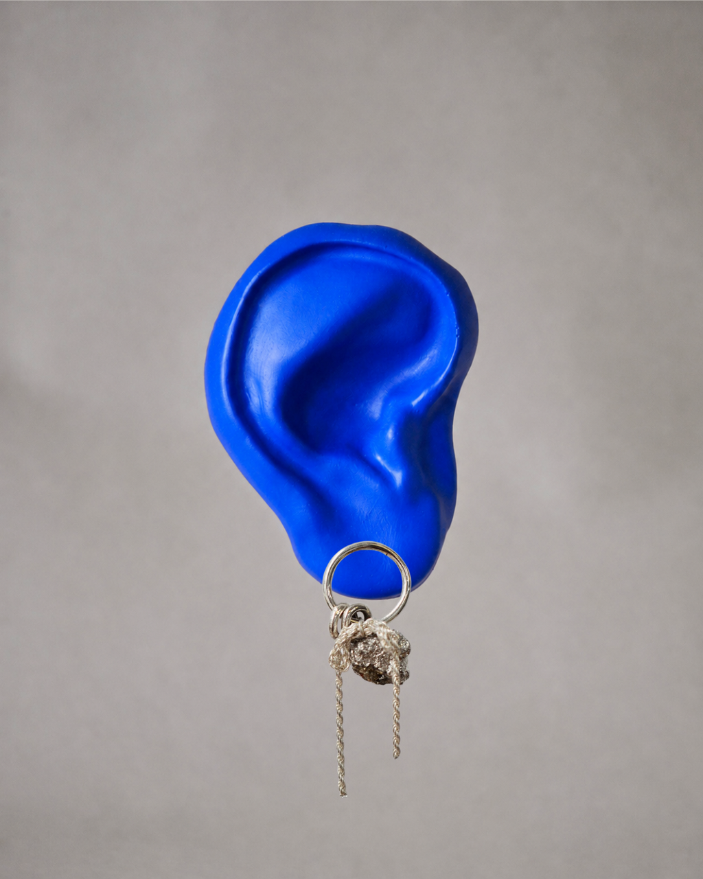 Silver forward facing hoop earring on a blue ear featuring pyrite crystal, ribbon chain, and silver hoops