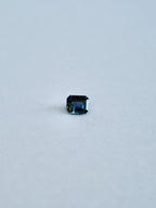 A loose emerald cut blue/green parti sapphire on a white background