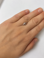 A single loose lozenge dusty pink zircon photographed on a persons hand for scale