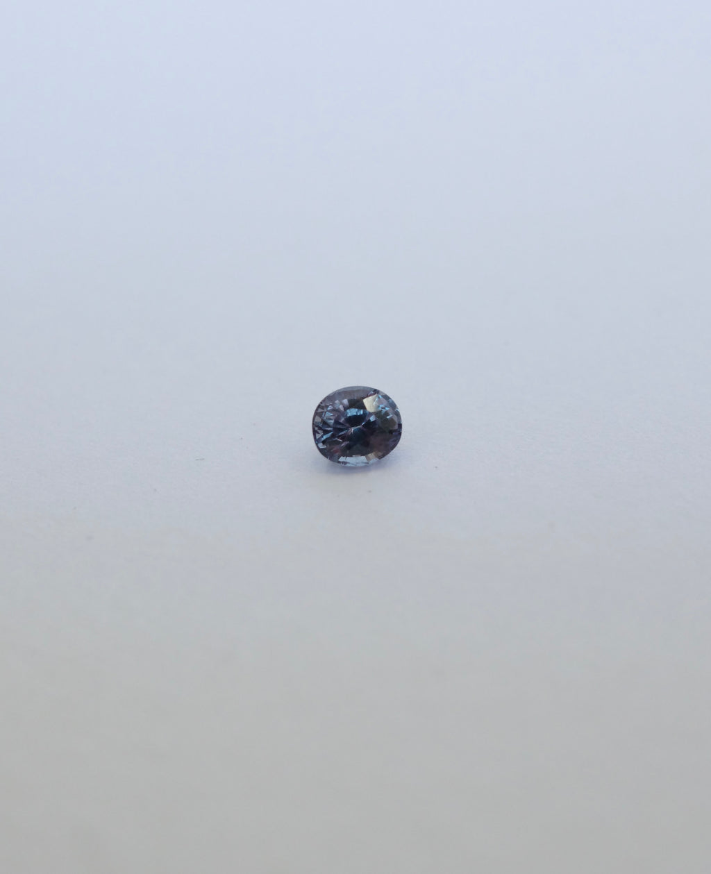 Oval brilliant cut colour chance loose sapphire on white background. Blue/purple in fluorescent light