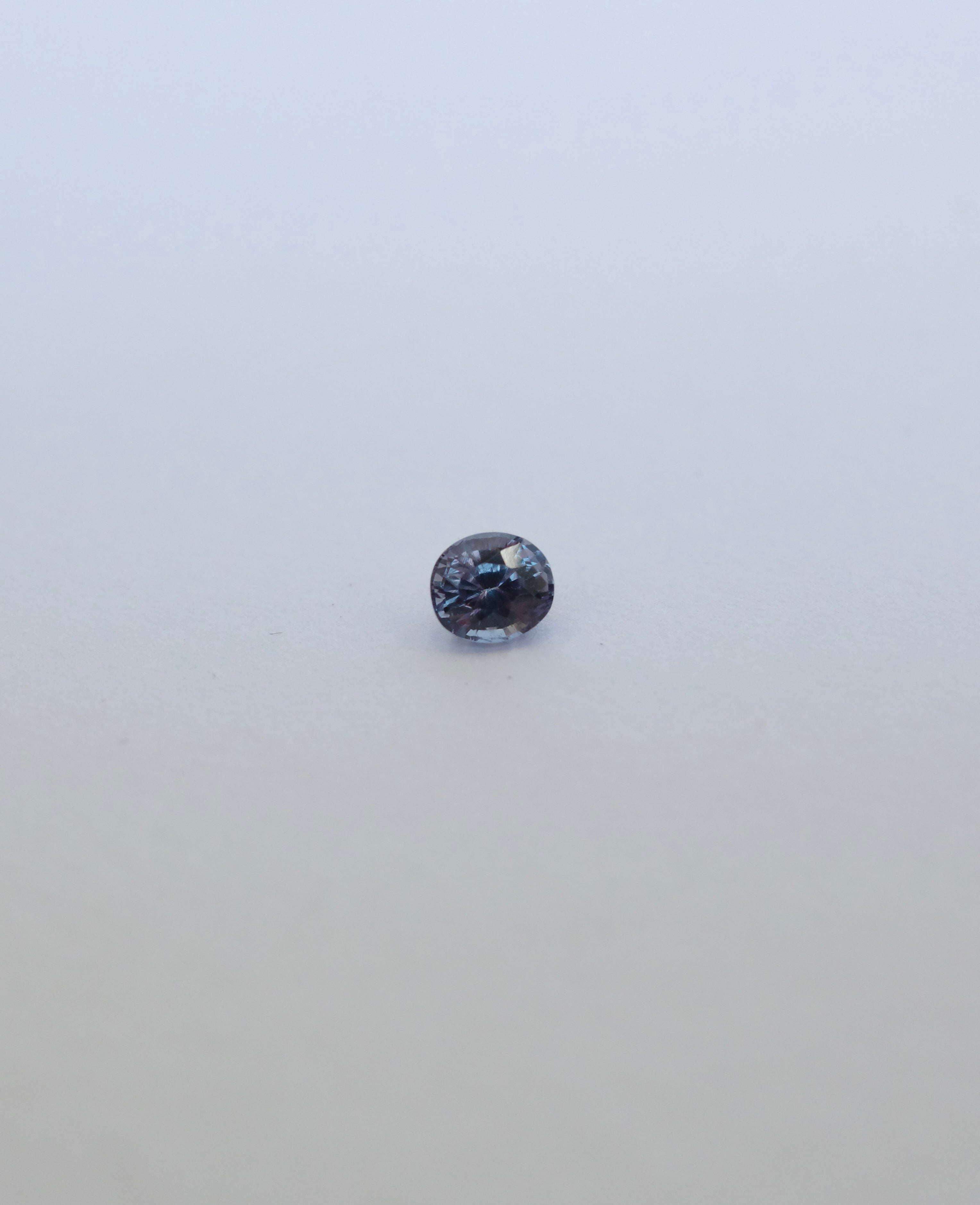 Oval brilliant cut colour chance loose sapphire on white background. Blue/purple in fluorescent light