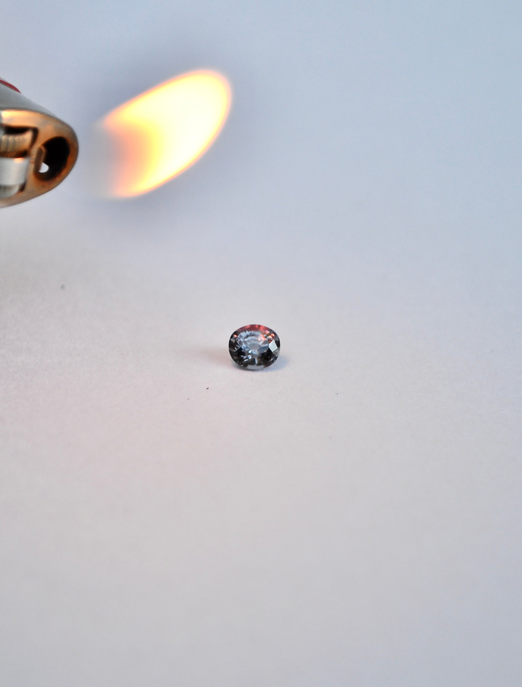 Oval brilliant cut colour change loose sapphire on white background. Purple/red in incandescent light