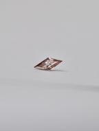 A single loose lozenge dusty pink zircon with a light pinkish-tinted clarity, photographed on a seamless light grey background.