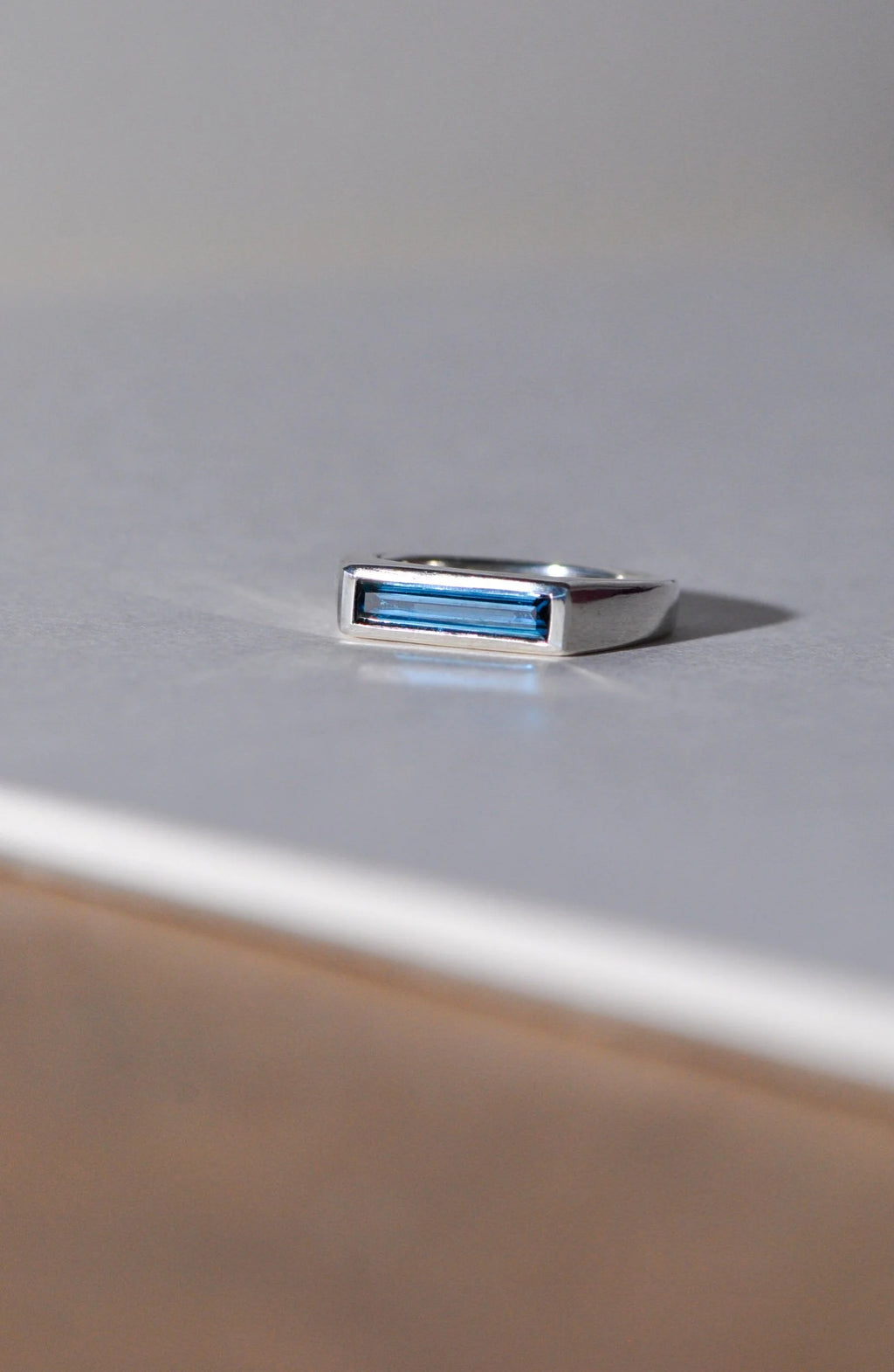 Silver ring with a london blue topaz on a light grey surface