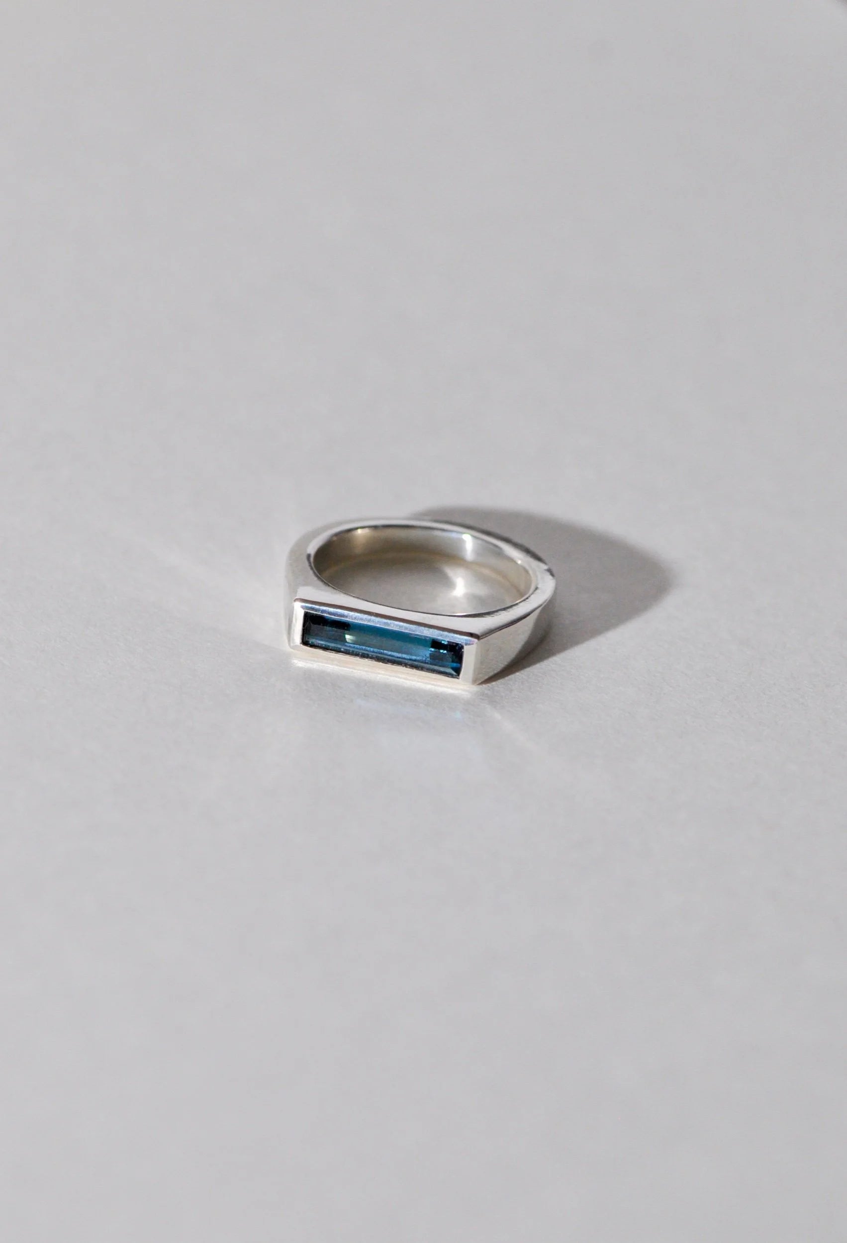 Silver ring with a London blue topaz on a light grey background