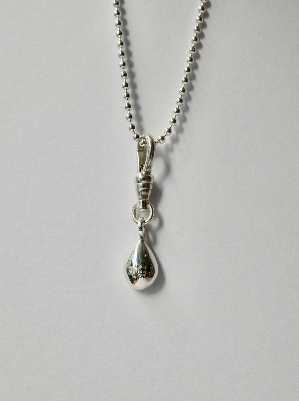A silver teardrop pendant necklace with a ball chain, shown against a plain light grey background.
