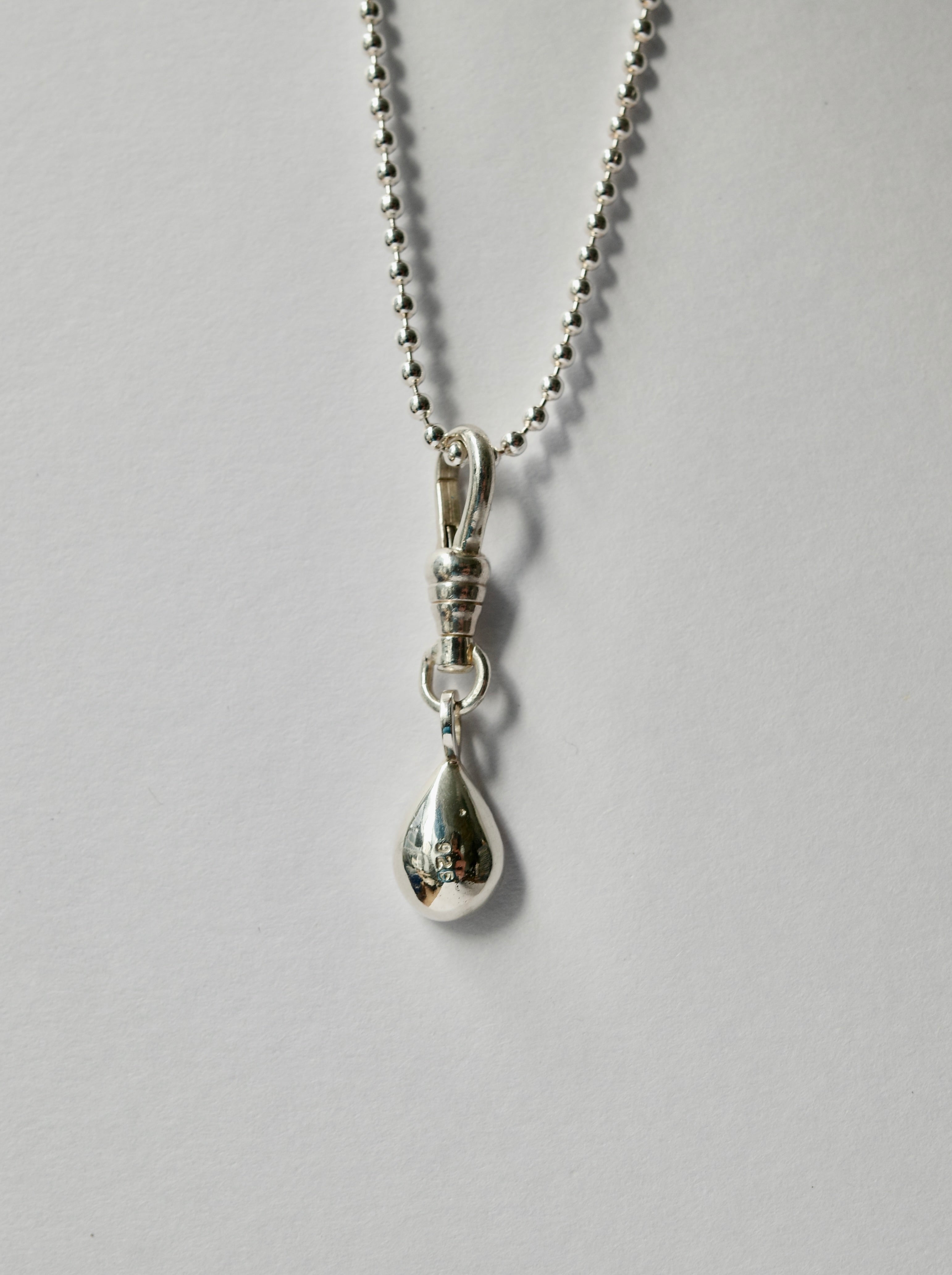 A silver teardrop pendant necklace with a ball chain, shown against a plain light grey background.